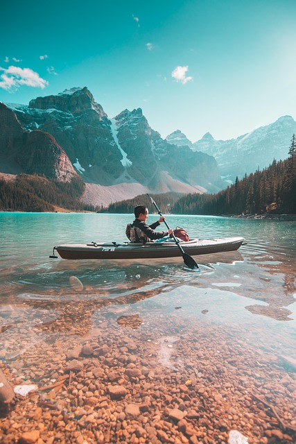 Kayaks on a clear blue lake surrounded by forests, suggesting adventure tours.